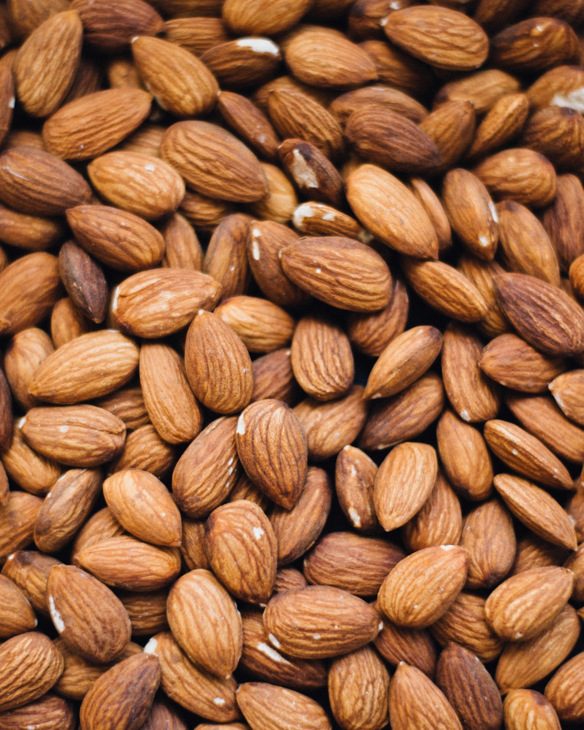 A dense pile of whole raw almonds with their skins intact