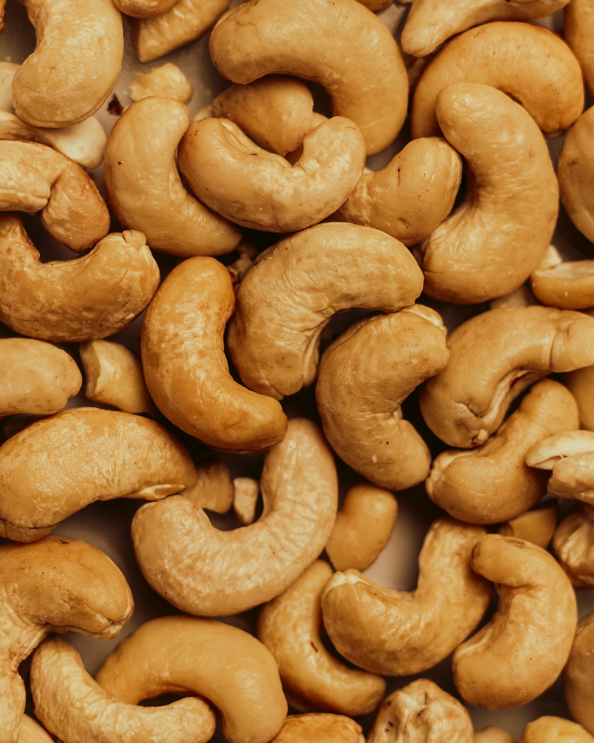 Close-up of whole roasted cashew kernels filling the frame